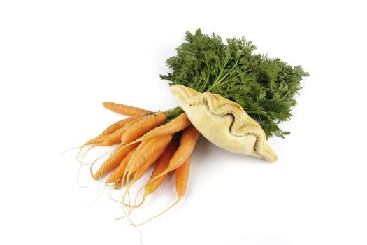 Contradiction between healthy food and junk food using bunch of carrots and pasty on a reflective white background 