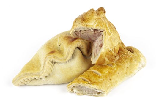 Single golden sausage roll cut in half with pork pie and pasty on a reflective white background