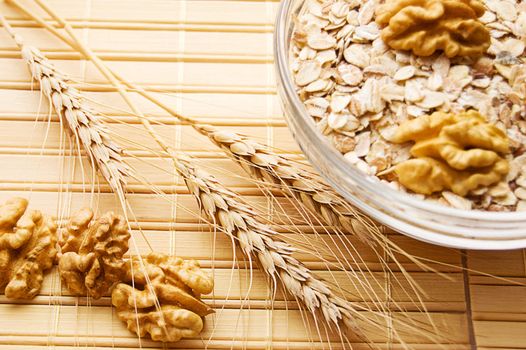 Bowl full of oatmeal with dry wheat and nuts, focus on wheat