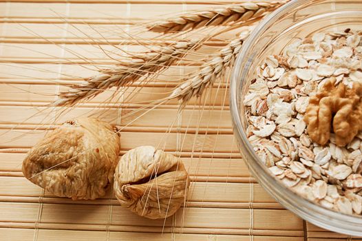 Oatmeal in bowl with nuts, figs and wheat