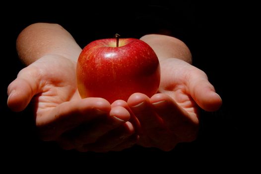 hand with red apple fruit on black background