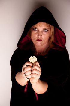 Witch in long black robe standing in corner with Talisman