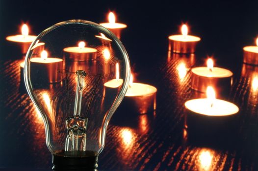 bulb and candle showing concept of saveing anergy
