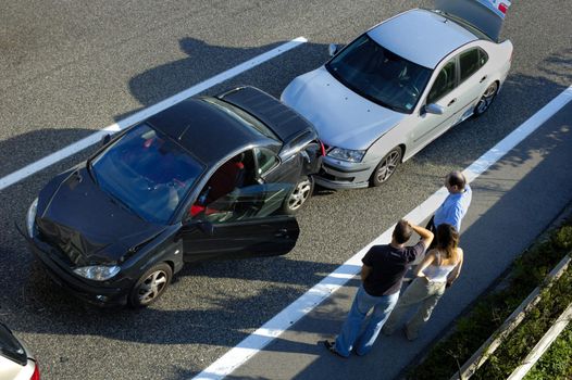 Three people stand by the roadside, discussing what has happened after a small shunt on the freeway (motorway, autoroute, autobahn).