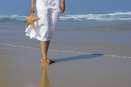 Beautiful woman on the beach with a starfish on the hand