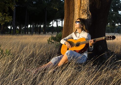 Woman playing her guitar at the sunset