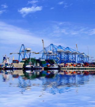 Detail of crane over stacked containers in freighting port in the Med