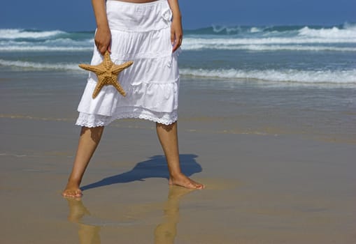 Beautiful woman on the beach with a starfish on the hand
