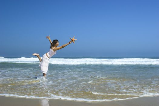 Beautiful woman feeling the breeze with a starfish on the hand