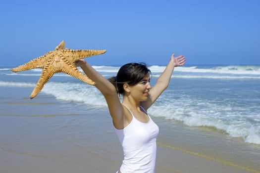 Beautiful woman on the beach felling the breeze with a starfish on the hand