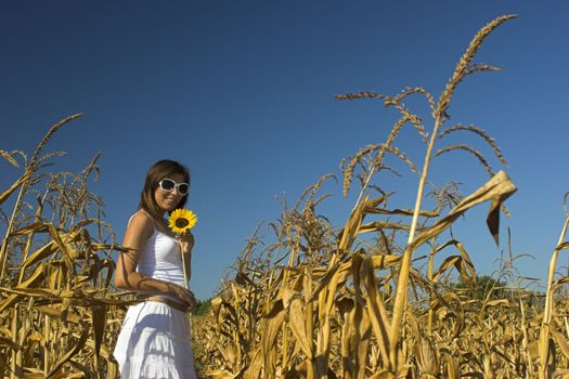 Beautiful woman with a white dress holding a sunflower 