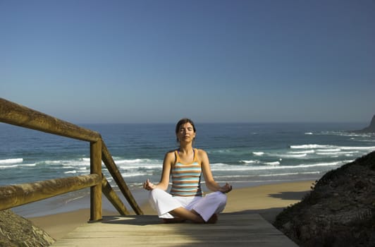 Beautiful young woman doing yoga on the beach