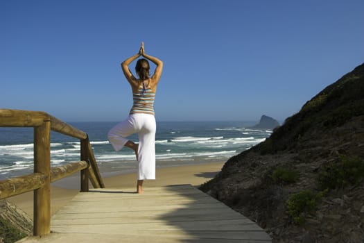 Beautiful young woman doing yoga on the beach