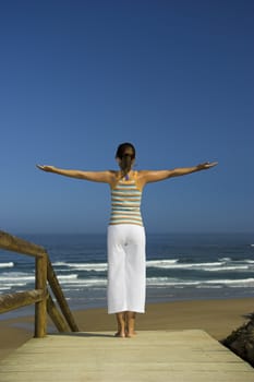 Beautiful young woman doing yoga on the beach