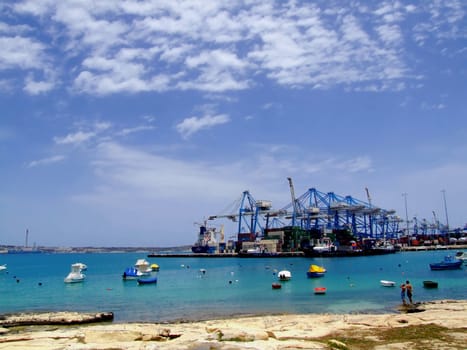 Detail of crane over stacked containers in freighting port in the Med