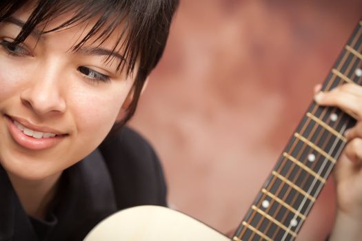 Attractive Ethnic Girl Enjoys Playing Her Guitar.