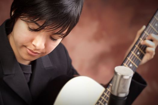 Attractive Ethnic Girl Enjoys Playing Her Guitar.