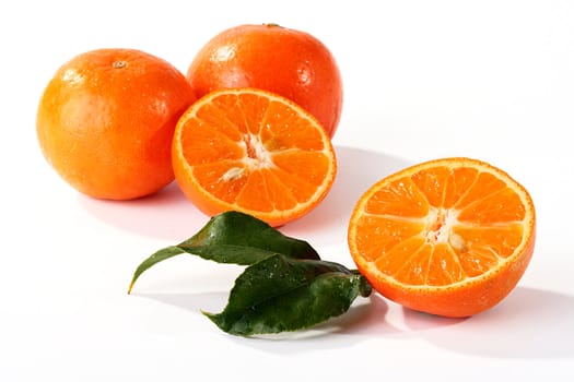 Half of a tangerine with leaves ������������� a tree, two tangerines on a back background.
