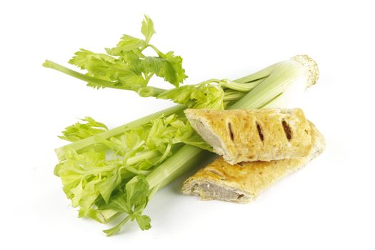 Contradiction between healthy food and junk food using celery and sausage roll on a reflective white background 