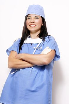 Nurse with crossed arms leaning on white wall.  Wearing a traditional blue scrubs uniform and stethoscope around her neck
