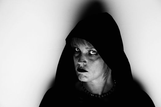 Witch in black hood standing in corner