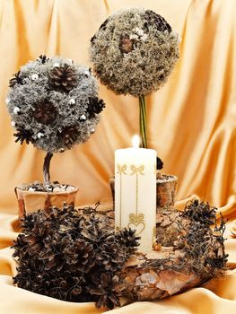 Christmas composition with candle, handmade garland and decorative trees against golden background