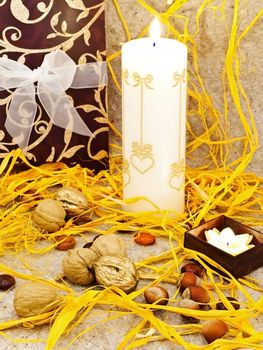 holiday decoration with gift box, candles and nuts against beige background