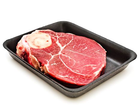 Big piece of raw meat at plastic plate against the white background 