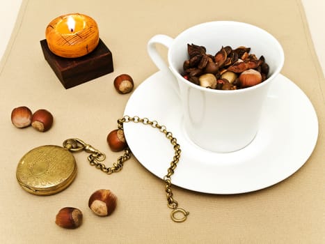 decorated table serving with candle, nuts and old pocket watch near cup at beige 
