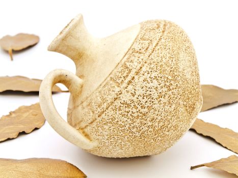 Close up photo of ancient beige vase and golden bay leaves against white background 