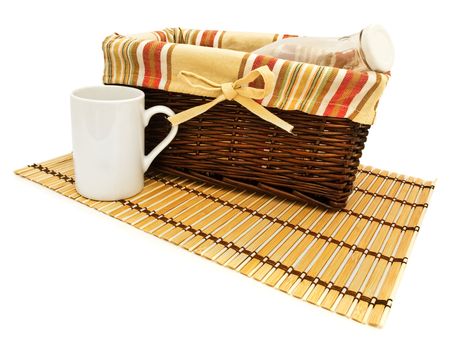 empty milk bottle in basket near white mug at bamboo mat over the white background 