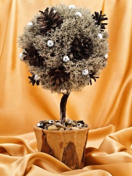 single decorative handmade natural materials tree against the golden textile background 