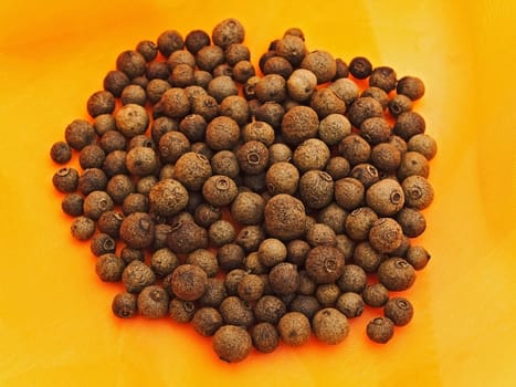 heap of allspice  over orange textile background