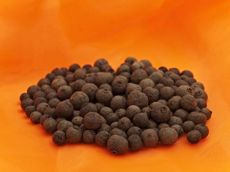 Photo of organic black pepper stack at orange textile