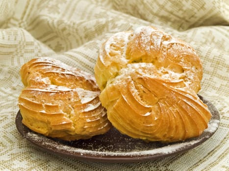 Two tasty buns with sugar powder against the linen background 