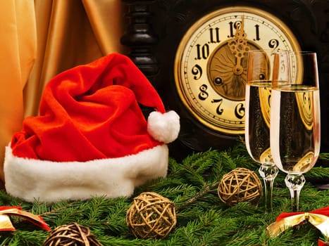 New Year composition with old clock, champagne, "Santa hat", fir and decorations 