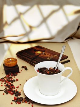 decorated table serving with burning candle, coffee beans near cup at beige