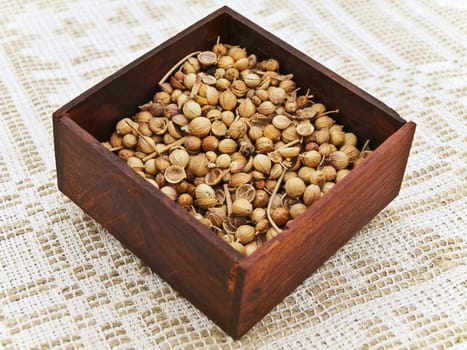 Coriander seeds at wooden box at linen handmade tablecloth
