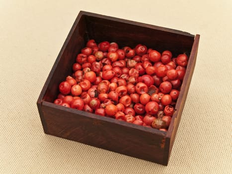 red pepper seeds in wooden box at beige textile