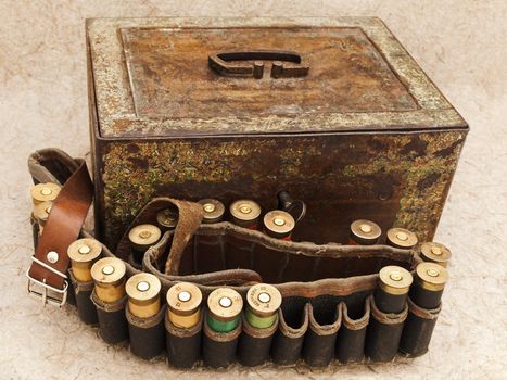 Photo of old cartridge for hunting rifle and vintage rusty chest against beige background