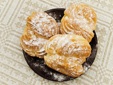 Three tasty buns with sugar powder against the linen background 