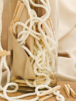 Composition with clothespins, cord and vase against beige textile background