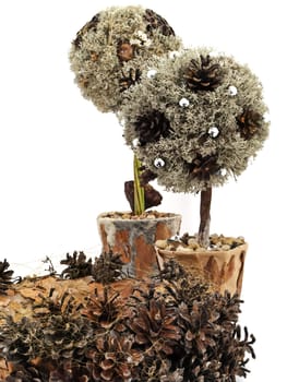 Two handmade decorative trees from pine tree and cones with wreath against the white background 