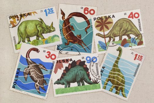 a variety of dinosaur species on vintage canceled post stamps from Poland placed casually on artist cotton canvas