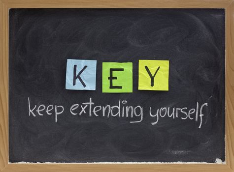 KEY (keep extending yourself) - coaching, motivational, self development acronym, white chalk handwriting and colorful sticky notes on blackboard