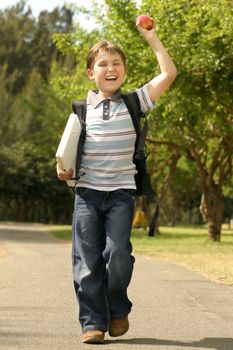 A jovial or enthusiastic child holding a laptop walks to school.
