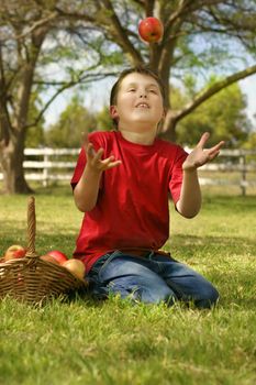 A child throwing and catching a red apple