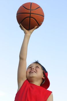 Boy in red shirt with a basketball against the sky
200 iso