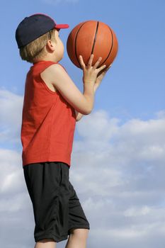 Child playing with  a basketball against a cloudy sky in afternoon.
200 iso