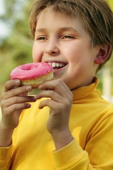 A child eating a pink iced doughnut